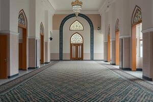 Empty mosque hallway with arched doorways, stained glass windows, and patterned carpet. photo