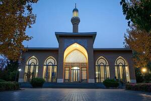 Illuminated mosque at dusk, architectural details visible. photo