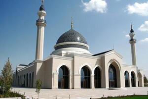Majestic beige mosque with blue dome, two minarets, and arched entrances under a clear sky. photo