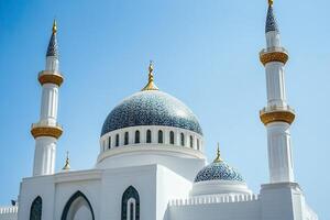 Majestic white mosque with blue dome and minarets against a clear blue sky. photo