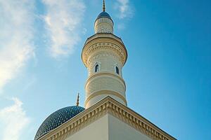 Low angle view of a mosque minaret against a blue sky. photo