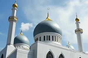 Majestic mosque with teal domes, gold accents, and minarets against a bright blue sky. photo