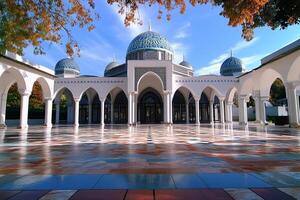 Majestic mosque with blue domes, surrounded by autumn trees and a reflective courtyard. photo