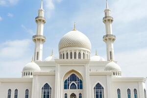 Majestic white mosque with two minarets under a blue sky. photo