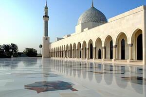 Mosque courtyard with reflective marble floor, arches, dome, and minaret under clear sky. photo