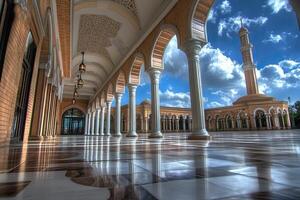 Mosque courtyard with arches, columns, and a minaret under a blue sky. photo
