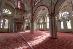 Sunlit interior of a mosque with stained-glass windows, arches, and ornate columns. photo