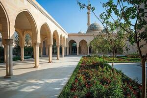 Sunlit courtyard with arched colonnade and mosque in background. photo