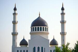 White mosque with two minarets and blue domes under a clear sky. photo