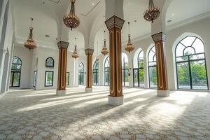 Sunlit mosque interior with ornate columns, chandeliers, and patterned carpet. photo