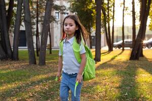Child exploring park with green backpack during golden hour photo