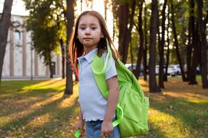 Girl with green backpack walking in autumn forest at sunset photo