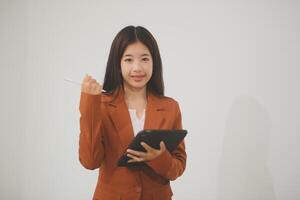 Young beautiful Asian woman in business office standing use tablet in hand, Thai girl enjoy browsing for online shopping store with copy space for advertisement, on isolated white background photo