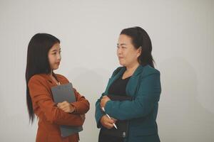Two young professional women looking at a digital tablet isolated on white background photo