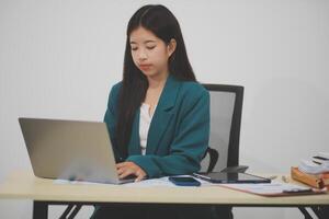 Beautiful Asian businesswoman work using a tablet and a laptop with documents placed at the office. photo