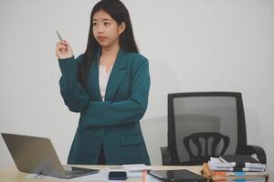 Asian Business woman using calculator and laptop for doing math finance on an office desk, tax, report, accounting, statistics, and analytical research concept photo