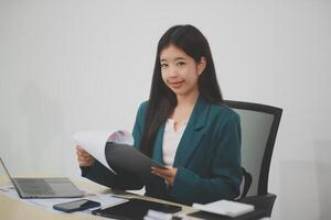 Asian business woman working using laptop computer, marketing report with calculator document on table Planning to analyze financial reports Investing in an online business plan, e-commerce. photo