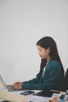 Beautiful Asian businesswoman work using a tablet and a laptop with documents placed at the office. photo