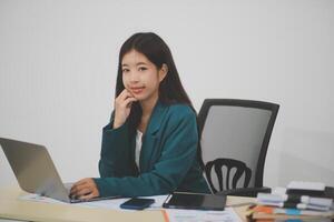 Beautiful Asian businesswoman work using a tablet and a laptop with documents placed at the office. photo