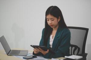 Beautiful Asian businesswoman work using a tablet and a laptop with documents placed at the office. photo