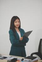 Asian Business woman using calculator and laptop for doing math finance on an office desk, tax, report, accounting, statistics, and analytical research concept photo