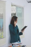 business woman working with laptop while consulting some invoice and document in working space at home photo
