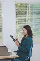 Asian professional businesswoman working on tablet computer in a corporate office photo