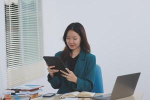 Asian professional businesswoman working on tablet computer in a corporate office photo