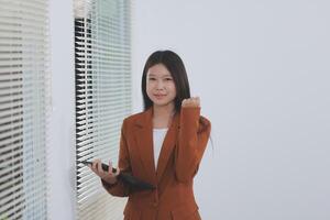 Happy relaxed young woman standing in home office using tablet, excited lady laughing holding tablet, enjoying doing online ecommerce shopping in mobile apps photo