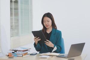 Asian professional businesswoman working on tablet computer in a corporate office photo