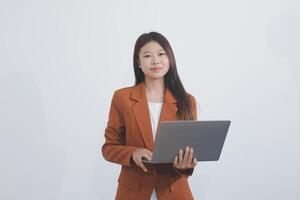 Attractive smiling Asian businesswoman standing holding tablet working and recording work details in office. photo
