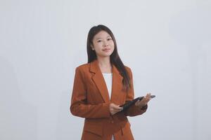 Attractive smiling Asian businesswoman standing holding tablet working and recording work details in office. photo