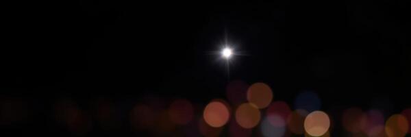 Illuminated night sky showcasing sparkling lights and a bright moon over a city landscape photo