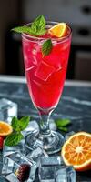 Refreshing red drink garnished with mint leaves and citrus slices on a marble table photo
