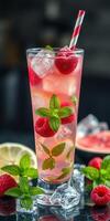 Refreshing raspberry lemonade cocktail served with mint leaves and ice in a tall glass photo