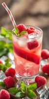 Refreshing raspberry beverage topped with mint and ice served on a wooden table photo