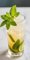 Refreshing mint and lime cocktail served in a tall glass with ice on a marble countertop photo