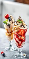 Delicious dessert sundaes with fresh strawberries, blueberries, and chocolate syrup served in clear glasses photo