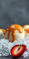 Delicious ice cream balls dripping with caramel sauce surrounded by ice and fresh strawberries photo