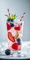 Refreshing berry drink with ice and mint served in a tall glass during a summer afternoon photo
