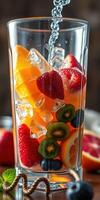 Refreshing fruit cocktail prepared with fresh strawberries, oranges, kiwis, and ice cubes in a tall glass photo