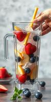Refreshing fruit smoothie preparation with fresh strawberries, blueberries, and ice in a clear blender photo
