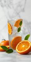 Refreshing orange beverage with slices and leaves arranged beautifully on a marble surface photo