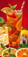 Refreshing summer drink with citrus and mint served in a tall glass against a vibrant red background photo