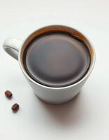 Hot coffee in a white cup with coffee beans on a light background near morning sunlight photo