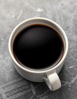 Hot cup of black coffee placed on textured gray surface in a cozy cafe setting during morning hours photo