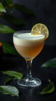 Refreshing cocktail garnished with lime served in elegant glass on dark background with green leaves photo