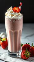 Refreshing strawberry milkshake topped with whipped cream and fresh strawberries served in a tall glass photo