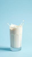 Splash of milk creates dynamic pattern in glass against soft blue background photo