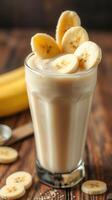 Creamy banana smoothie topped with fresh banana slices on a rustic wooden table photo